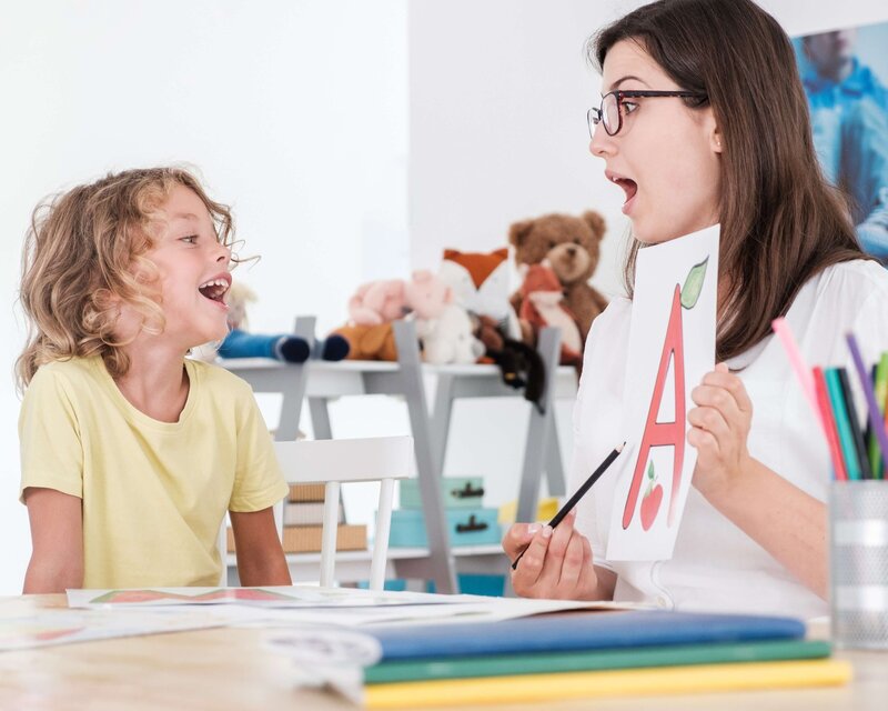 Speech-language pathologist working with a young child on letter recognition during a therapy session in a bright, child-friendly room in Clinton, NJ.