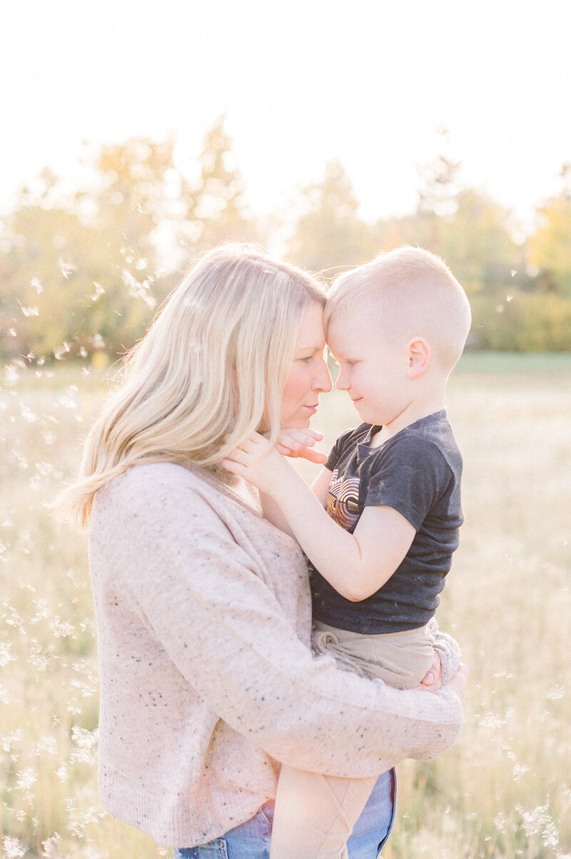 Mother and son forehead to forehead smiling at each other in the prairies.