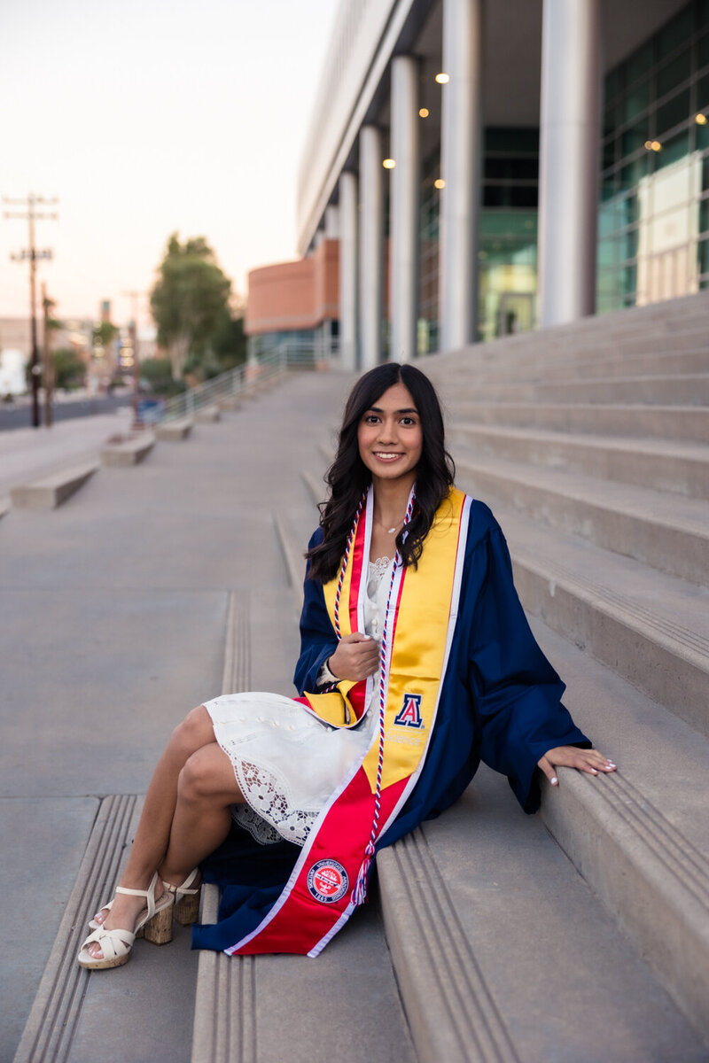 college graduate sitting on stairs