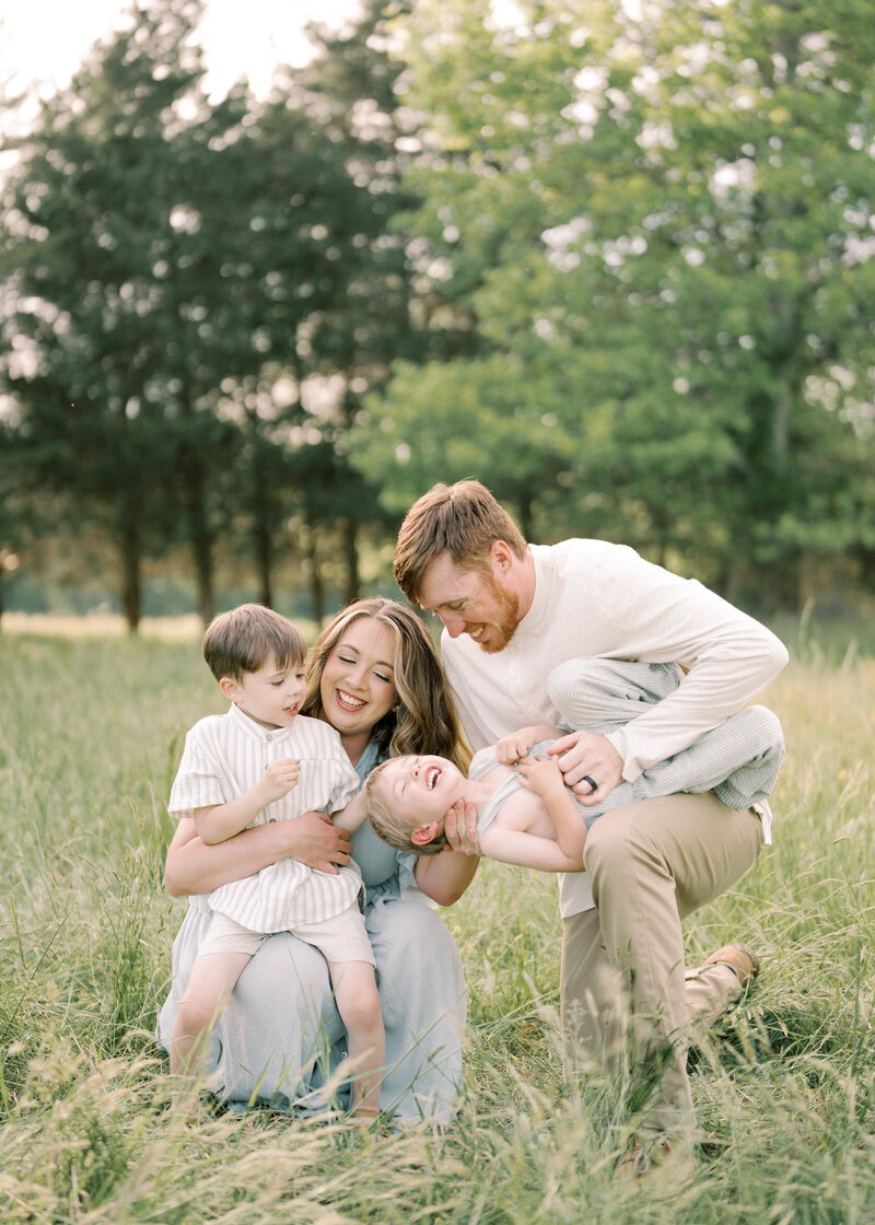 Mother hugging son and dad tickling younger child family cuddling.