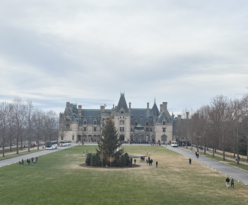 Scenic view of the historic Biltmore Estate in Asheville, NC with visitors walking across the front lawn. 