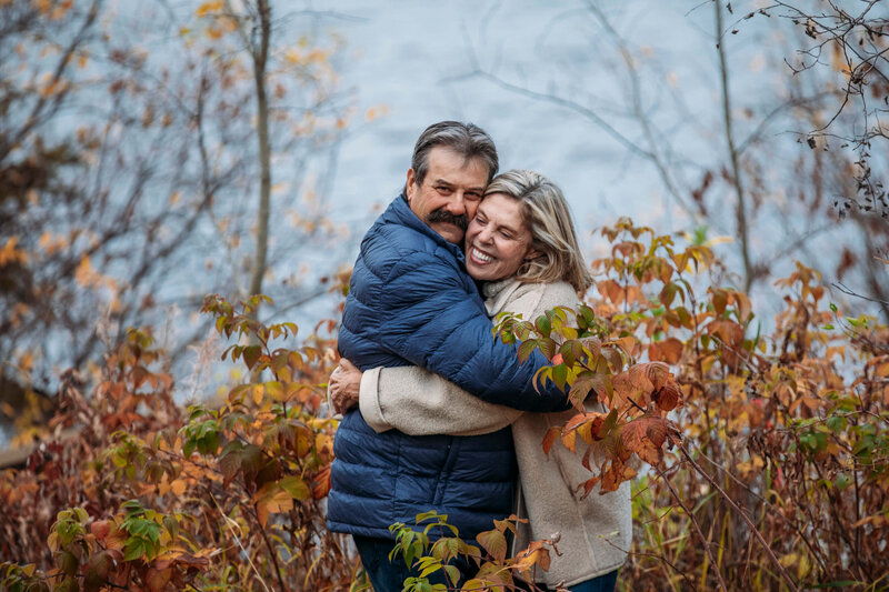 couple hugs and laughs in the fall foliage