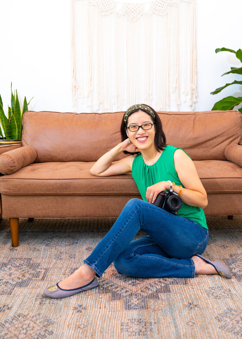 An Asian woman sitting comfortably on a wicker chair for her branding photoshoot at a co-working space in  Pennsylvania.