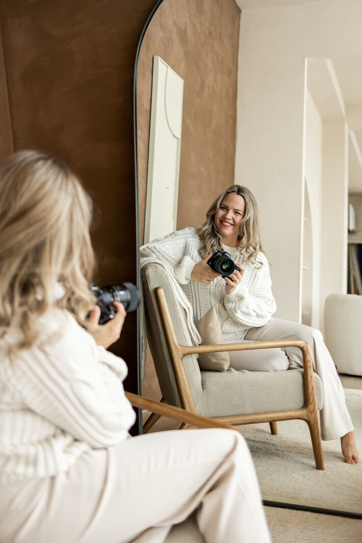 Juliette Laurant lachend met camera in haar hand kijkent in de spiegel