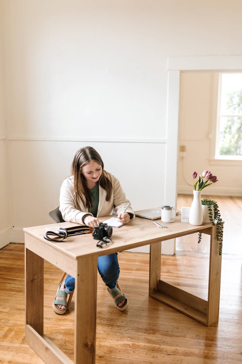 McKenna Fahrenbruch, digital marketing expert at Graceful Exposure Media, sitting at her desk with her DSLR camera and notepad—planning content shoots and creative strategy for small business clients.
