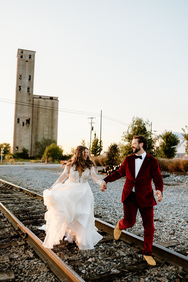 newlyweds running on train tracks
