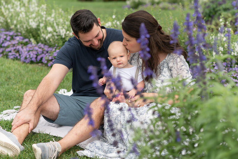 Family sitting in garden, smiling at young son