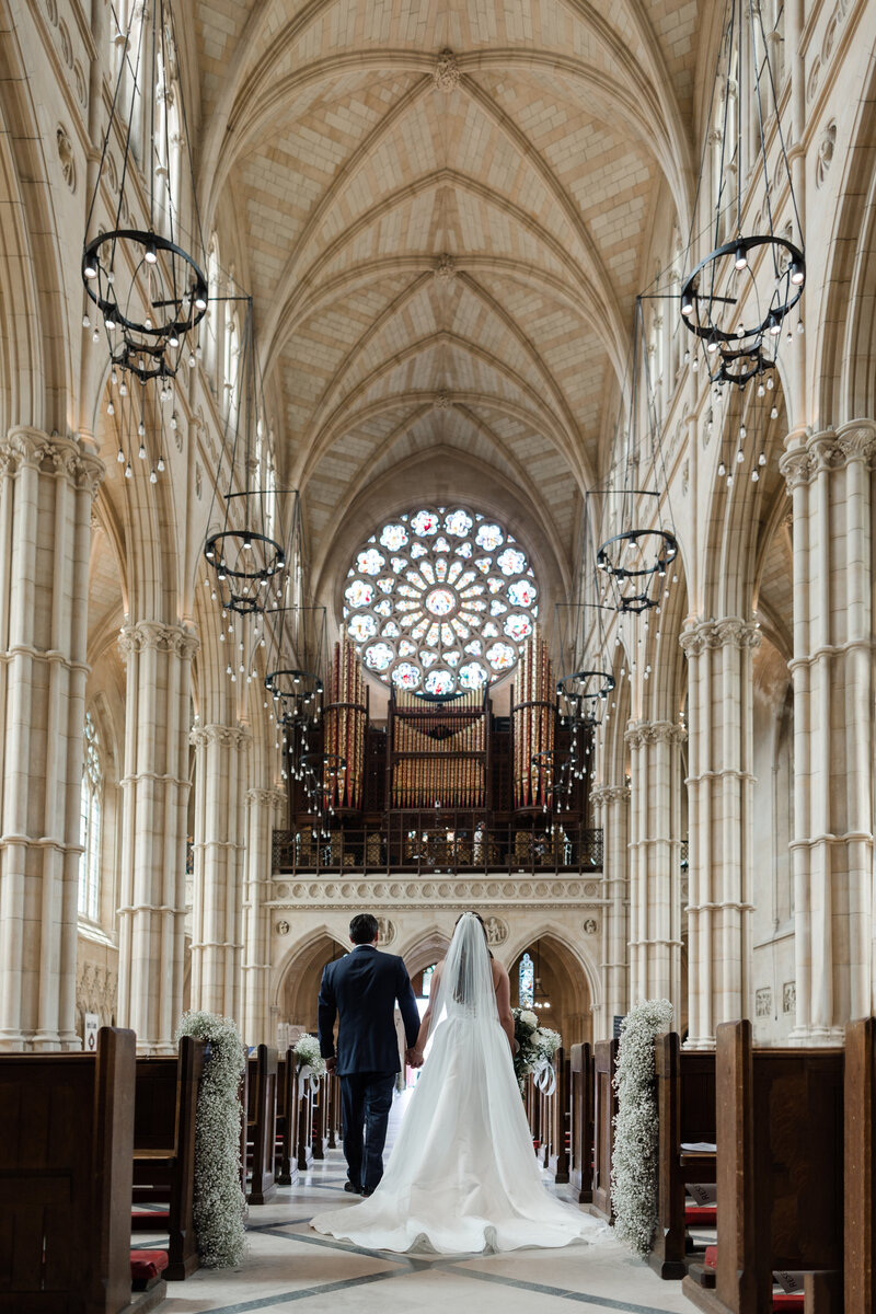 Grand wedding photo of bride and groom exiting the aisle at Arundel Cathedral showing the cathedrals beautiful architecture and stained windows