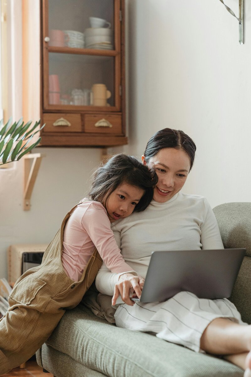 Smiling mom and child looking at computer, representing connection, resilience, and perinatal mental health counseling.