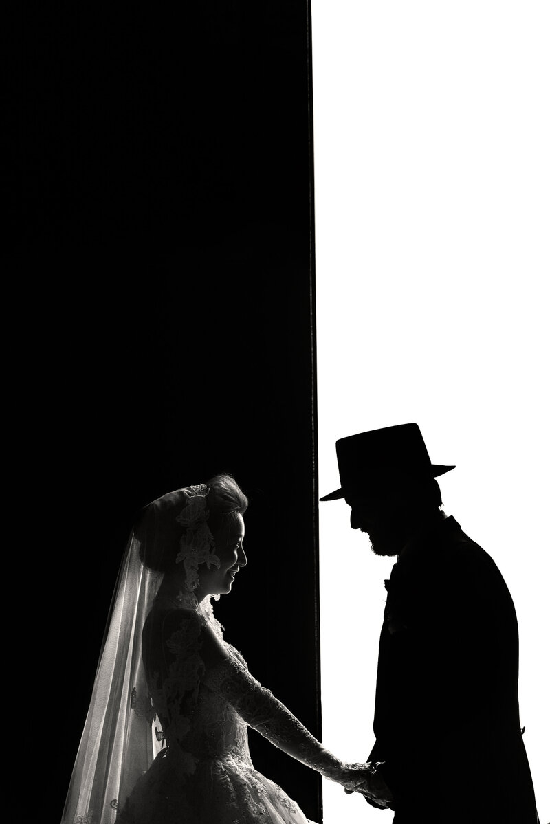 A bride against a black background holding hands with a groom set against a white background.