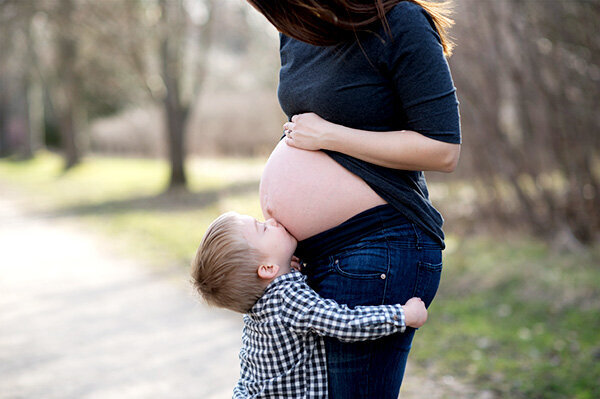 Chelsey Maternity session with first born child. Boy kissing baby belly