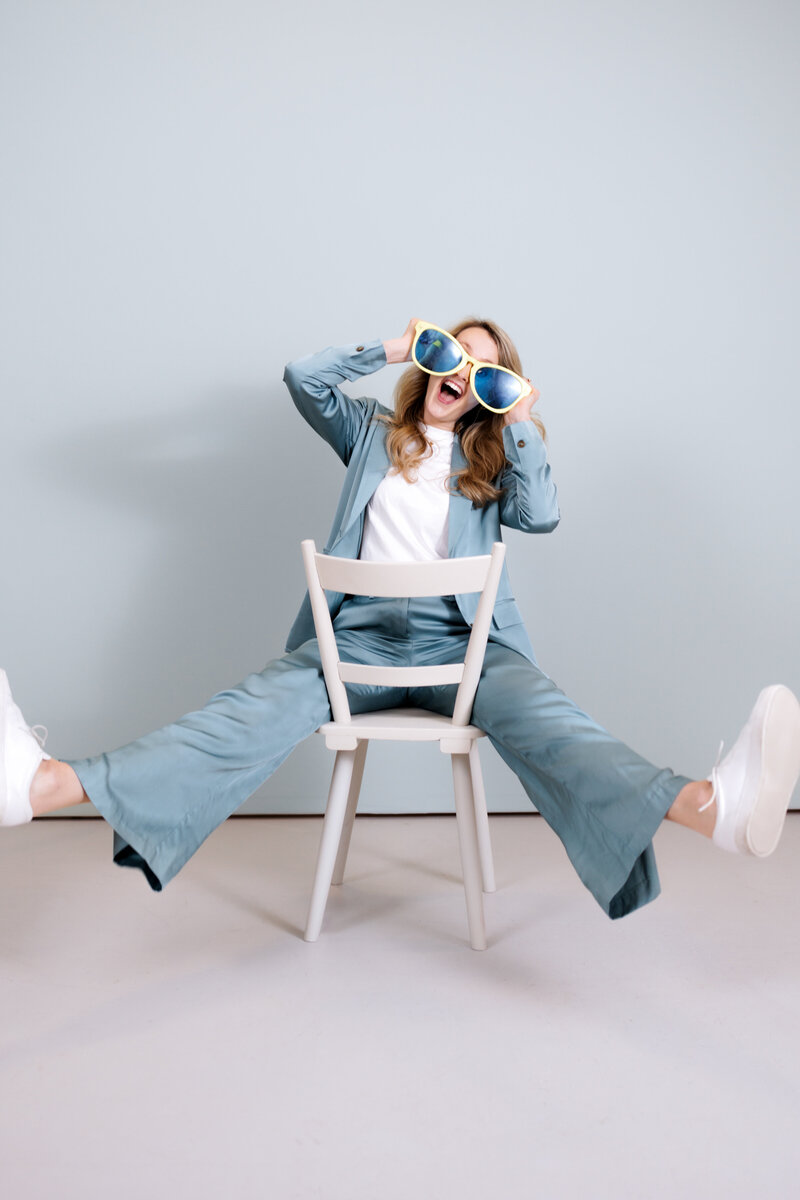 Valerie Greene in blue suit and white top with silly blu large sunglasses