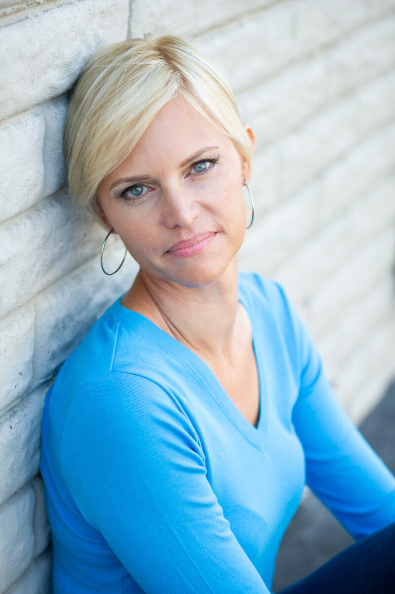 Professional Headshot of a caucasian woman with short pixie bob hair and blue shirt.