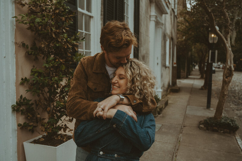 couple sitting on sidewalk with skateboard