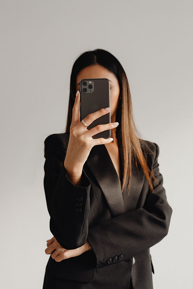 kaboompics_dark-classy-aesthetic-fashion-beautiful-asian-female-entrepreneur-in-black-suit-technology-and-devices-iphone-laptop-airpods-30095