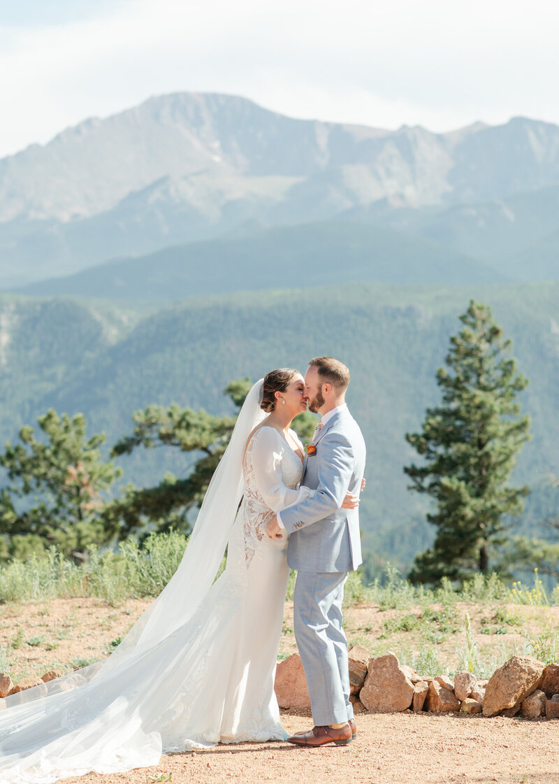 Brian and Theresa standing in front of mountains having their first kiss as husband and wife.
