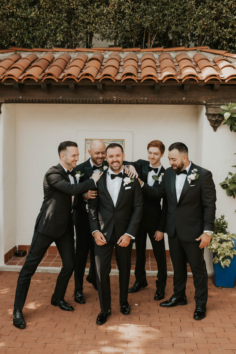 Groom and Groomsmen smiling in luxury black tuxedos
