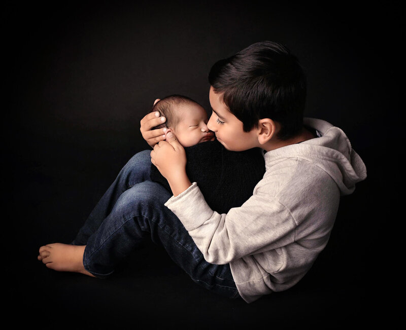 Older brother and newborn posing nose to nose  at a newborn photography session.