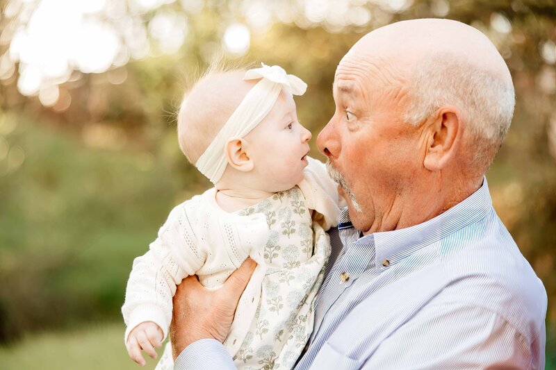 up close portrait of grandfather making silly face at baby granddaughter