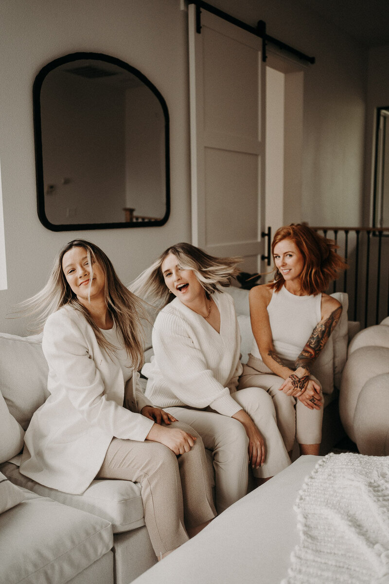 three girls flipping their hair while sitting on the couch