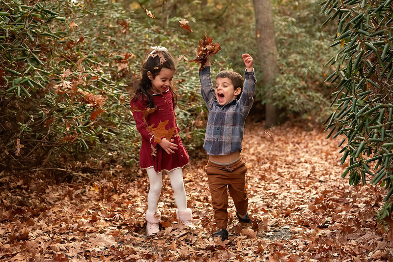 Kids are throwing leaves during a family photo session at Whip Hill Park.