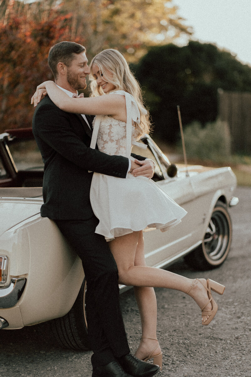 Bride and Groom leaning against a car