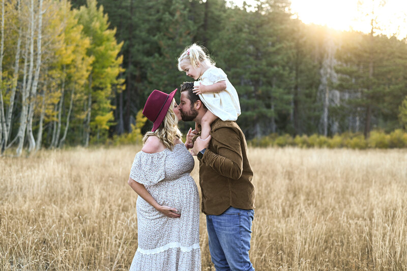 Husband and wife kiss at maternity session. 