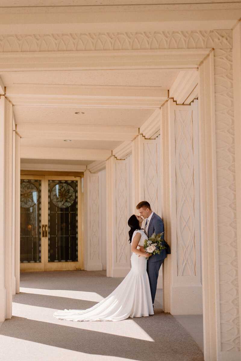 Bride and groom leaning against pillar at the LDS Gilbert Temple