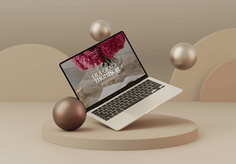 A laptop mockup showcasing the Lila Grace Thompson website. The laptop is floating in a 3D scene with abstract shapes and metallic spheres.