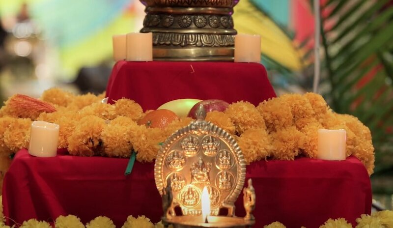 Colorful flowers and fruits on a tiered table with a candle in front 