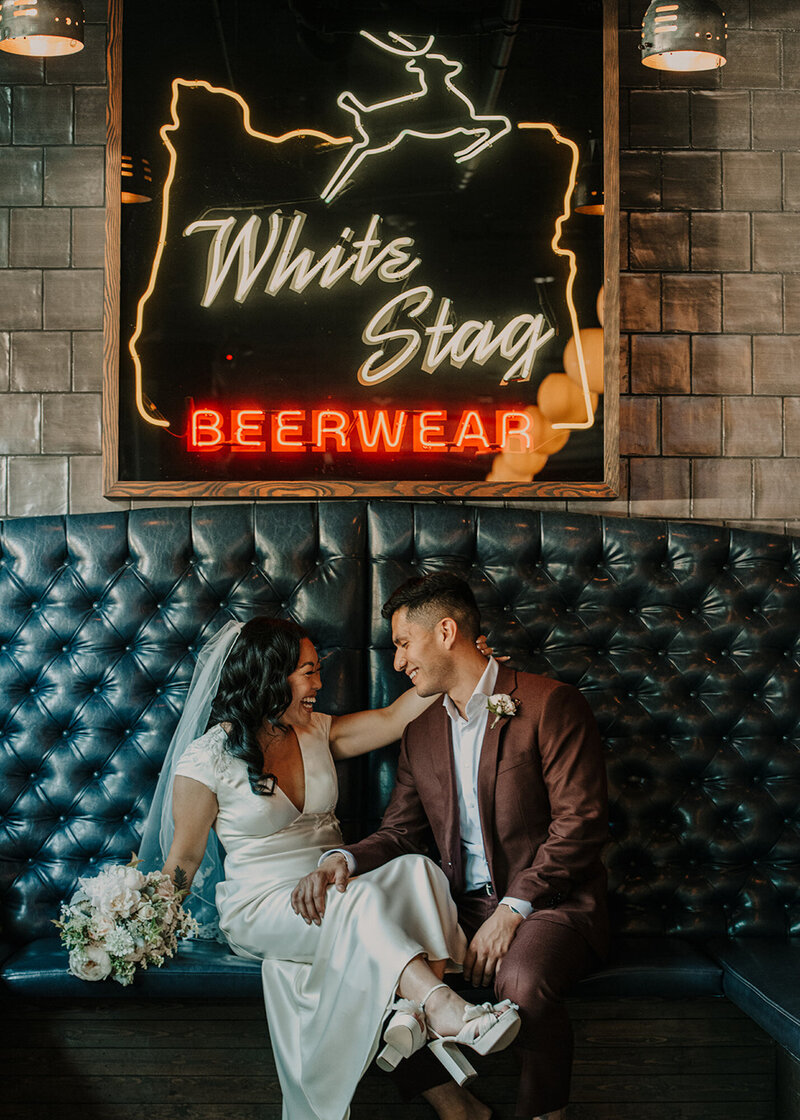 Bride and groom sitting down on a luxurious black couch