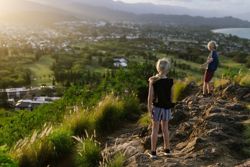 Two children walk along the rocky edge along an outlook at Kailua Lanikai pillbox.
