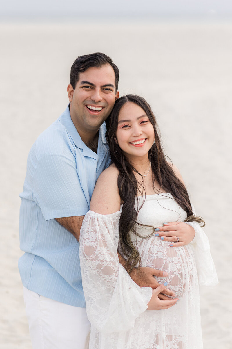 father and pregnant mother in sand