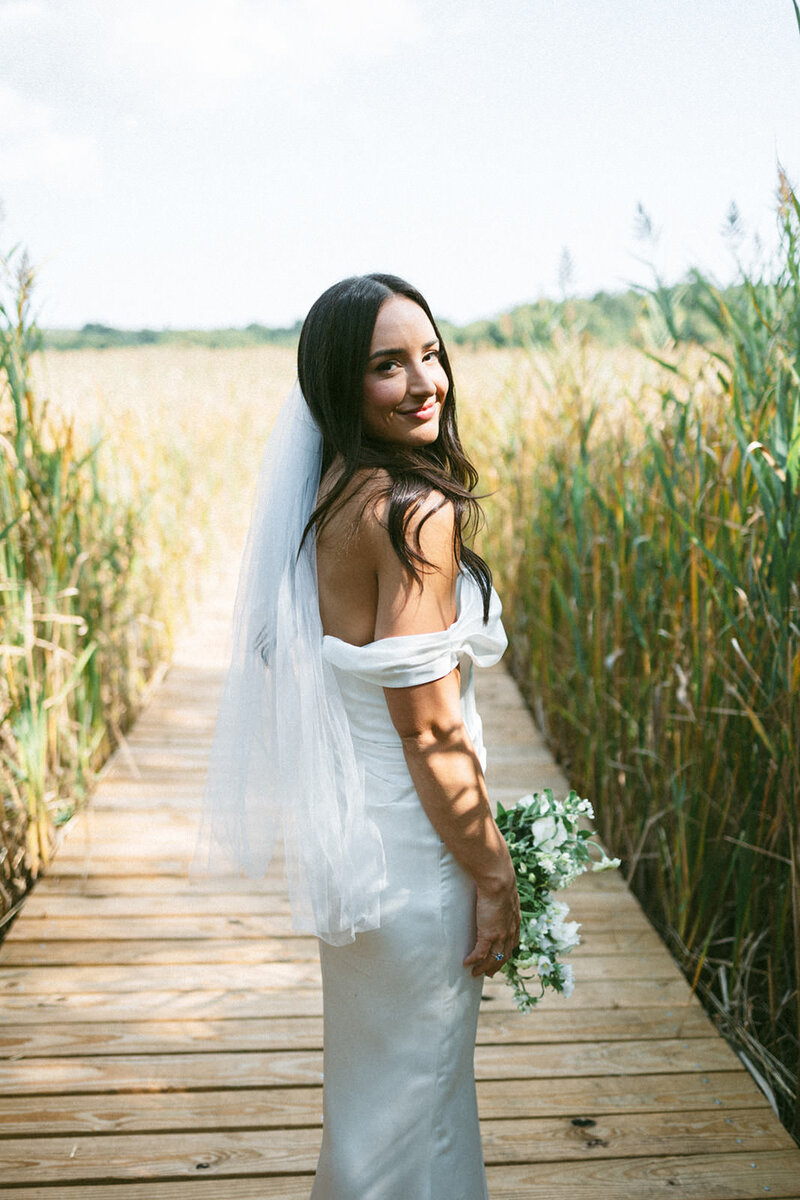 Stunning bridal portraits on a boardwalk surrounded by dunes at her coastal wedding 