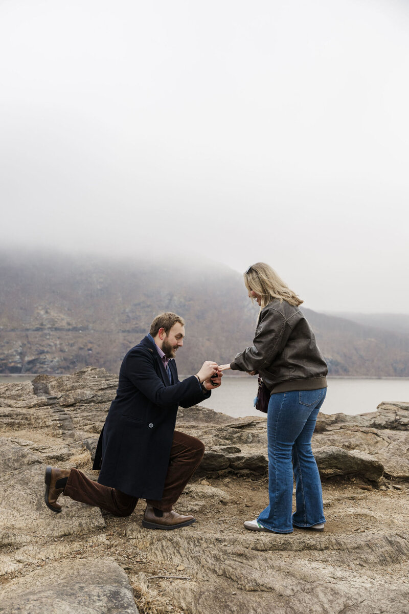 Man down on one knee proposing on a foggy mountain overlook in a Hudson Valley proposal photo