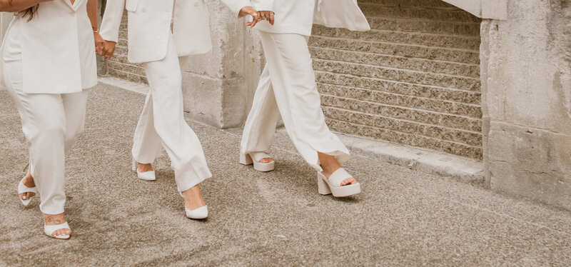 two successful businesswomen dressed in white suits walking on the sidewalk in a big city