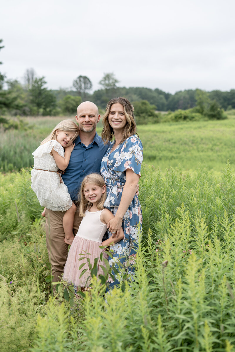 Family of four smiling at camera in field