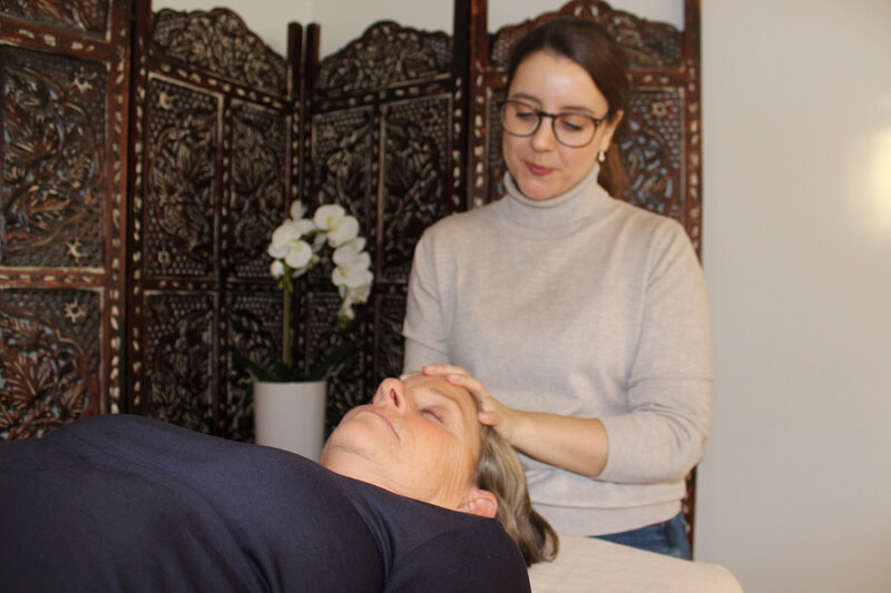 Craniosacral treatment. Therapist gently touching clients head