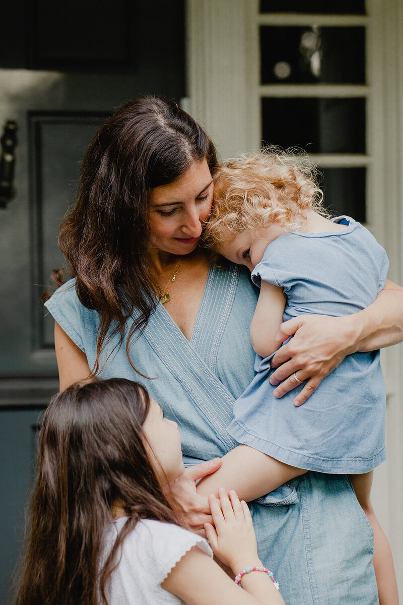 A mother cuddles with her two daughters outside their home in Ohio