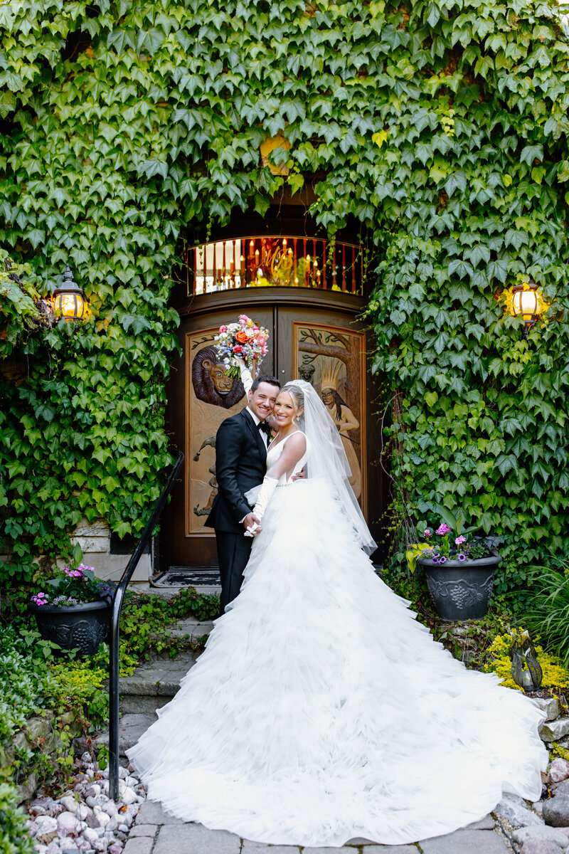 Bride and groom embrace in front of ivy covered building