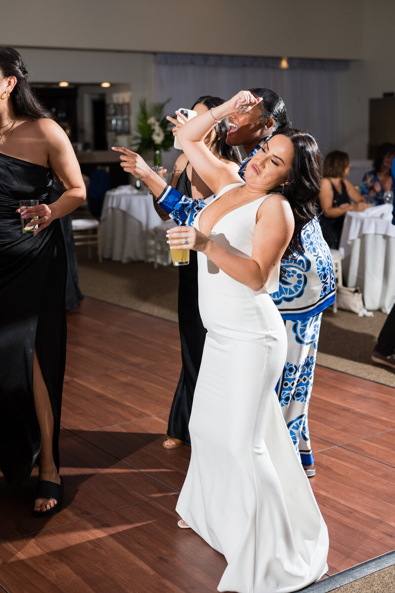 Bride dancing joyfully at the Emerald at Queensridge reception, surrounded by guests and glowing candlelight.