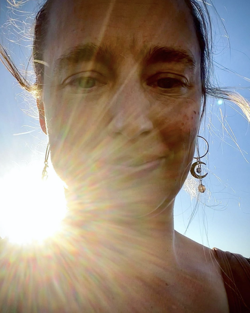 close up of woman's face with sun beam behind her