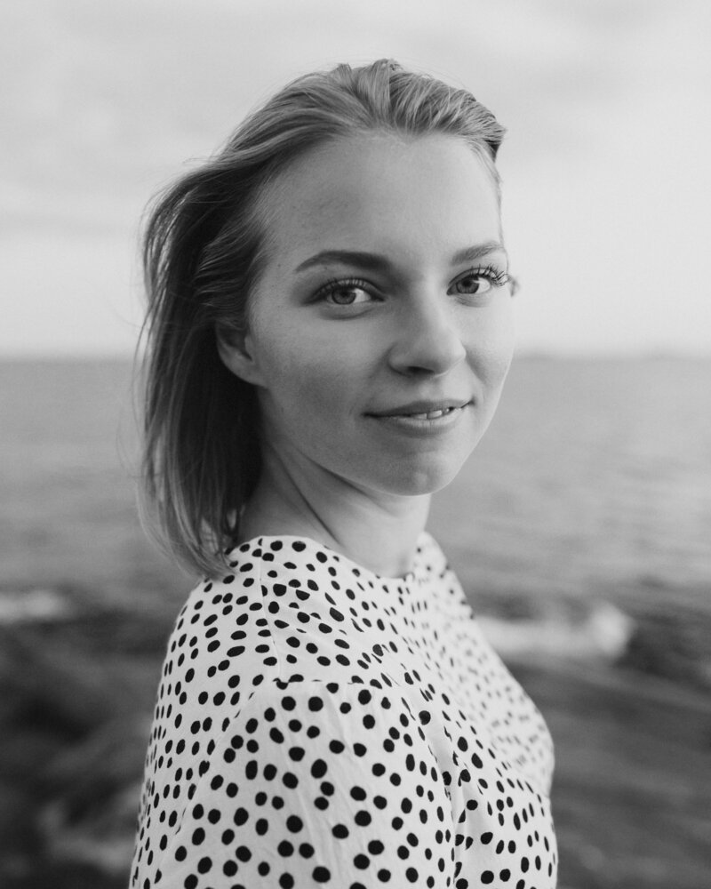 Portrait of a woman standing and lookin to the camera and smiling gently in Helsinki in Finland