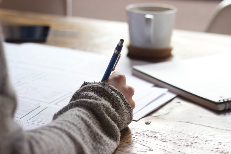 Woman at table writing in a notebook