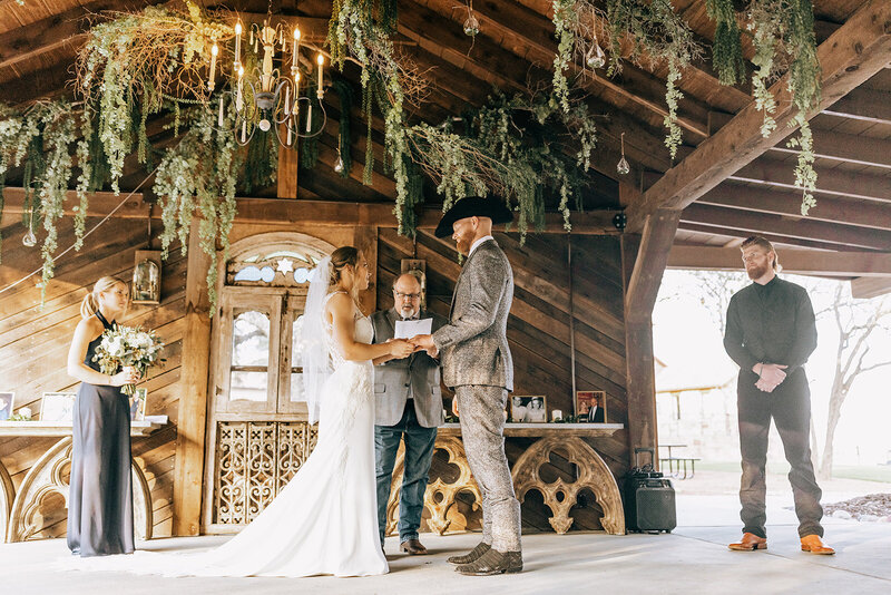 bride and groom exchanging vows in rustic barn wedding venue