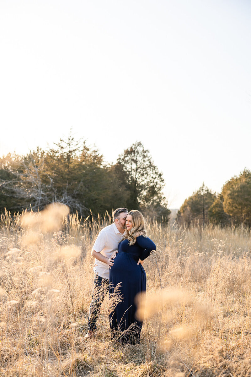 Expecting couple in a sunlit field during golden hour maternity session in Farmington Missouri.