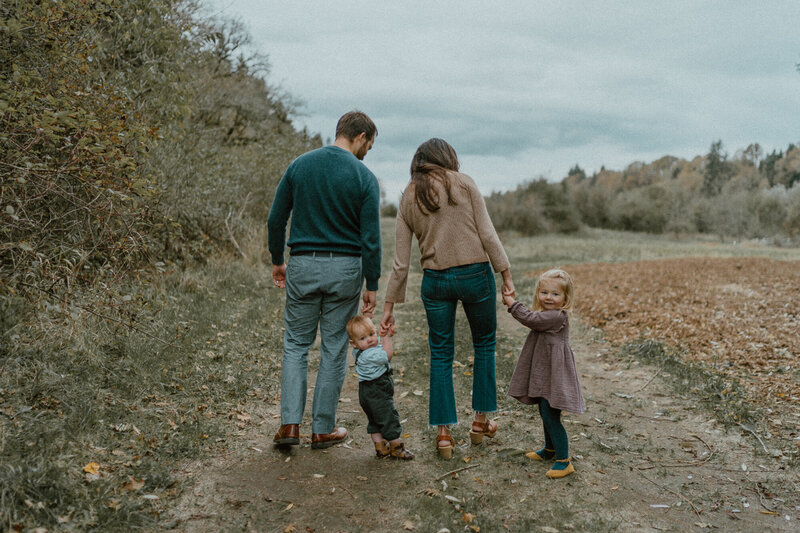 family walking on trail with backs to camera and holding hands