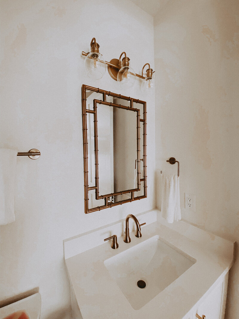 white bathroom with gold mirror