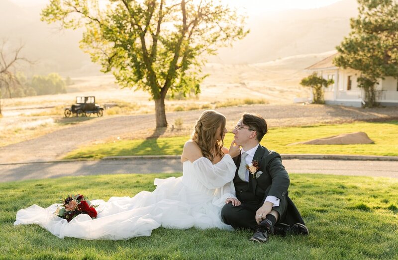 bride and groom laying on the front lawn at The Manor House wedding venue in Littleton, Colorado romantically embracing during golden hour