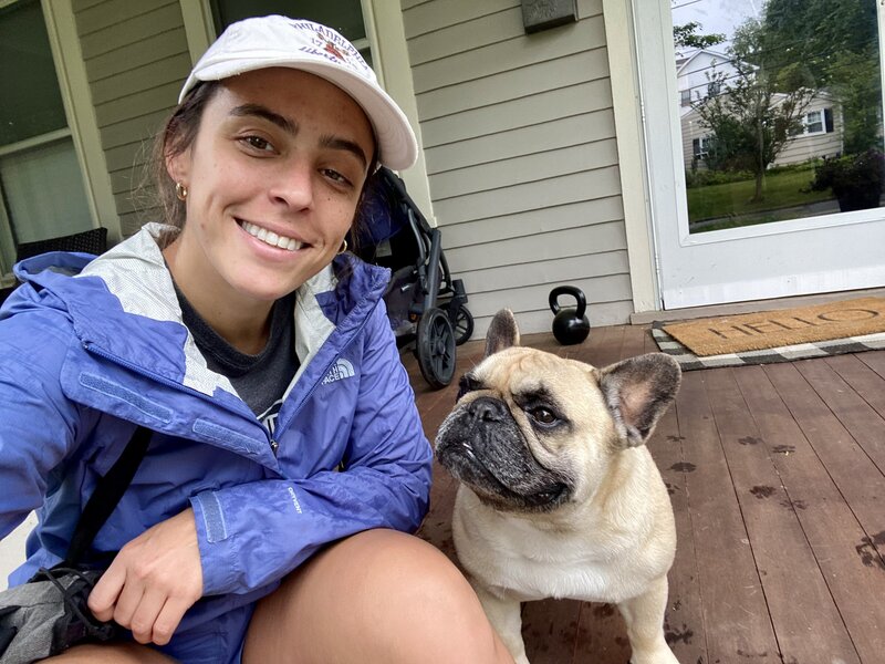 woman and frenchie dog smiling on porch steps on a rainy day